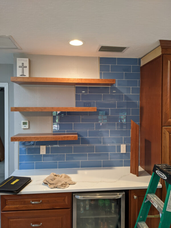 Custom floating wood shelves installed over a tile backsplash by Rescue Remodeling in Palm Bay FL
