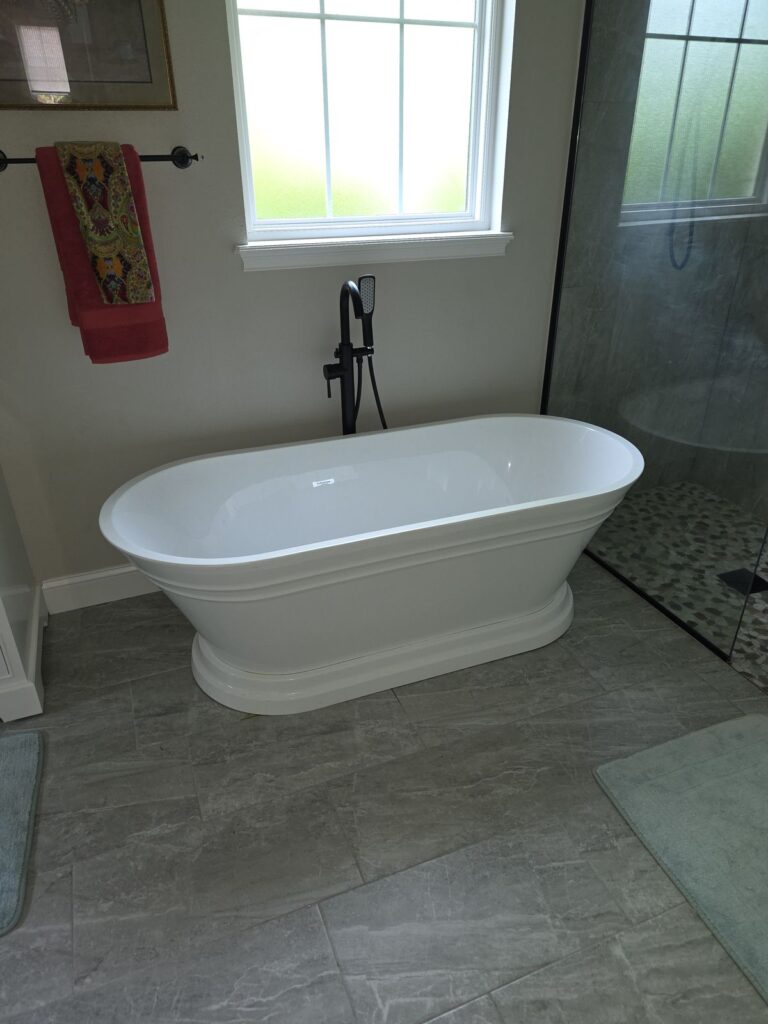 Freestanding soaking tub on gray tile floor