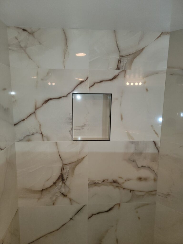 Marble-look tile shower wall with recessed niche