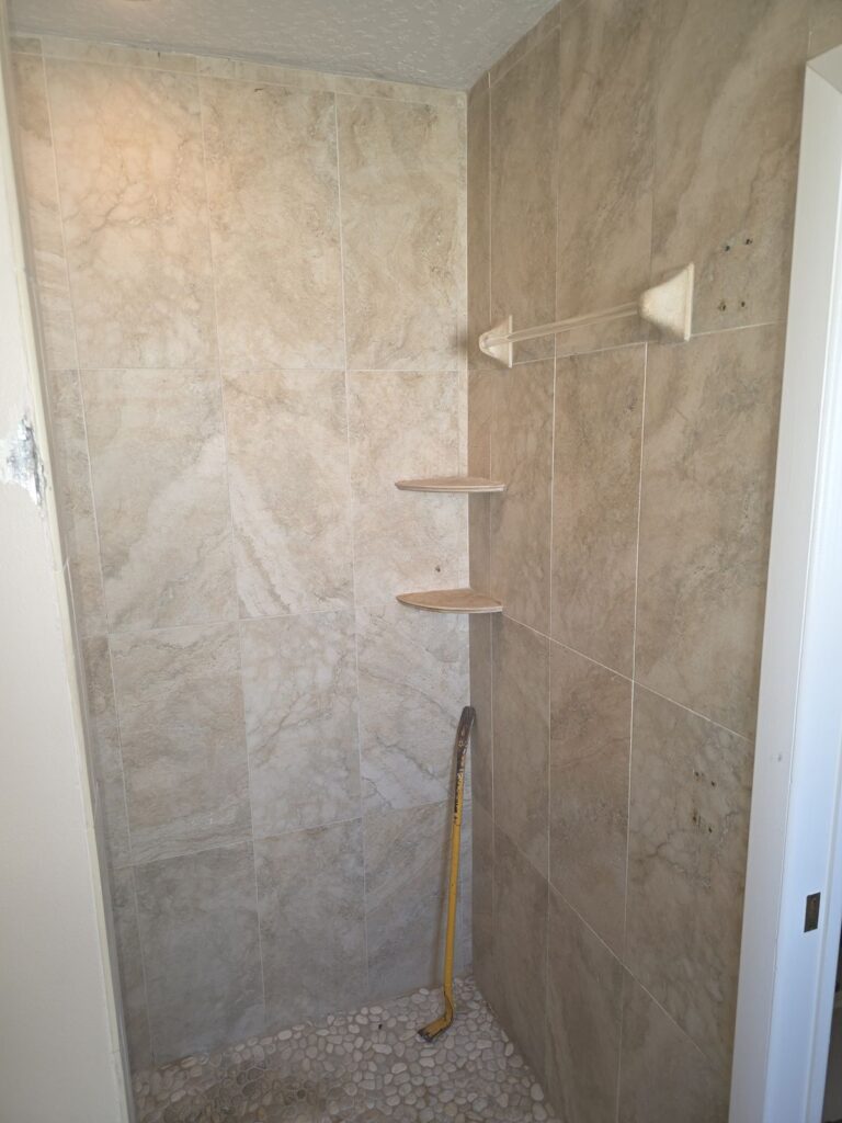Tan tile shower with corner shelves