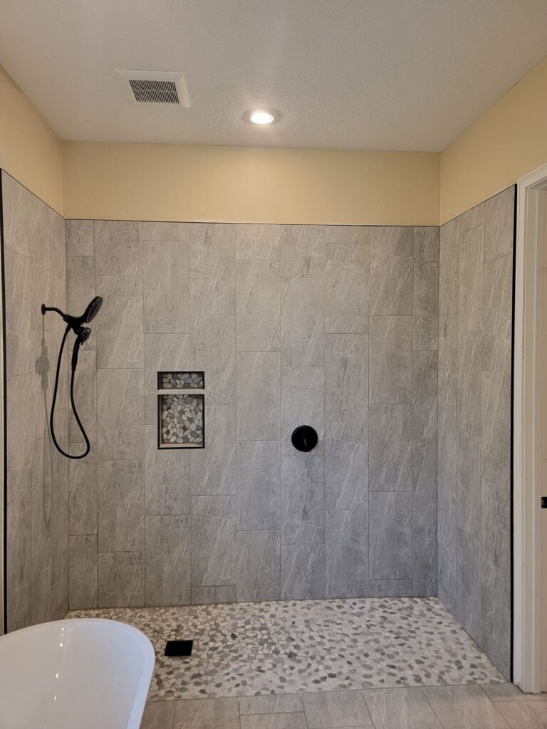 Walk-in shower with pebble floor and black fixtures