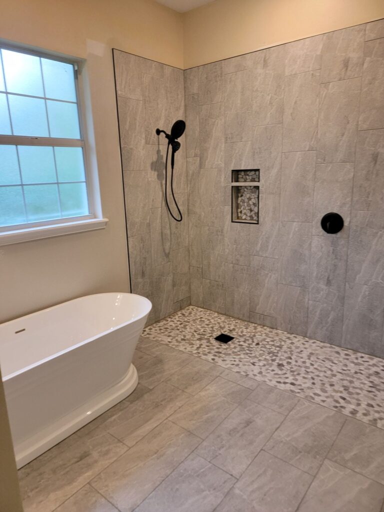 Open walk-in shower beside a freestanding tub